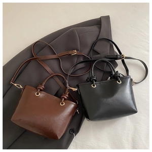 Detail of stylish brown and black bucket bags with knot design and gold metal rings