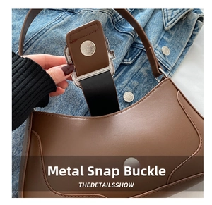 Detail of silver magnetic hardware buckle on brown leather shoulder bag close-up