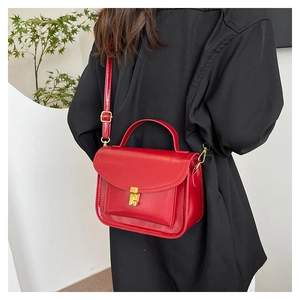 Detail of red glossy shoulder bag featuring golden metallic buckle and adjustable strap