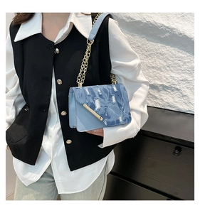 Dettaglio borsa a tracolla in denim azzurro con catena dorata e fibbia in metallo