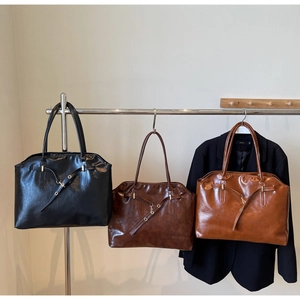 Three glossy faux leather tote bags in black, dark brown, and caramel colors on display