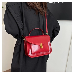 Detail of red leather crossbody bag with golden twist lock and glossy oil-wax finish