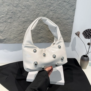 Sac à bandoulière blanc brillant avec rivets argentés sur fond en pierre pour femme