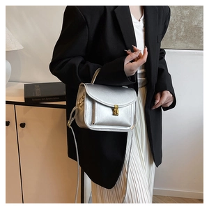 Silver metallic crossbody bag with gold square buckle shown hanging on a model wrist