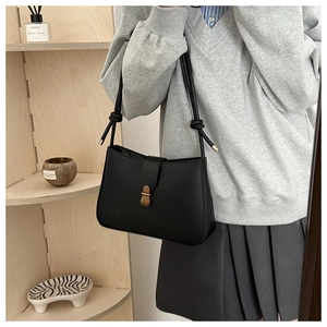 Detail of black underarm bag featuring a knotted shoulder strap and vintage gold buckle