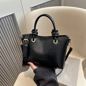 Black glossy leather bucket bag with knot handle and gold hardware for daily commute