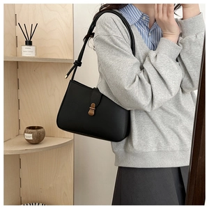 Detail of black leather underarm bag with bronze buckle and decorative knot shoulder strap