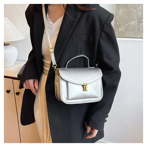 Détail d'un mini sac carré argenté avec fermoir doré et texture en cuir métallisé