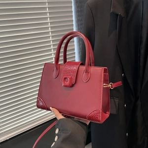 Borsa a tracolla rosso scuro con trama a coccodrillo su sfondo blazer nero