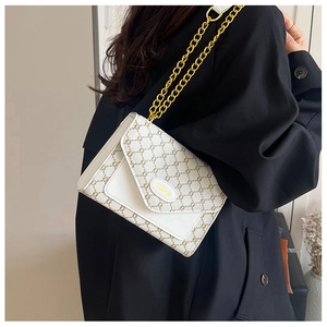 Détail du sac bandoulière vintage blanc avec motif monogramme et chaîne dorée