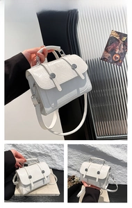 Detail view of white crinkled patent leather crossbody bag with silver buckles and strap