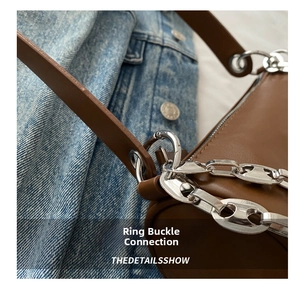 Detail view of brown leather strap with silver ring buckle and hollow metal chain
