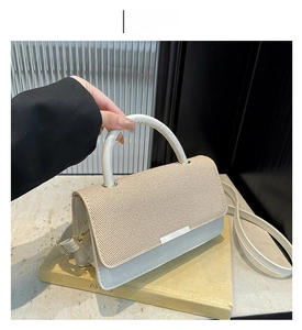 Détail du sac bandoulière en cuir PU blanc avec rabat tissé sur un livre décoratif