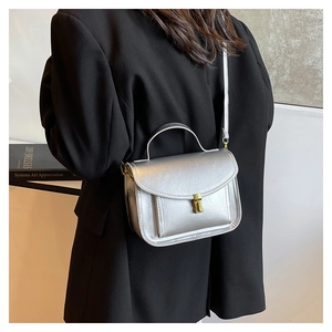 Silver metallic leather crossbody bag with buckle detail worn by a model in a studio