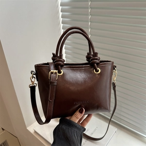 Brown bucket bag with knot handle and gold hardware, shown in a lifestyle scene