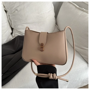 Detail of vintage apricot shoulder bag featuring brass metal buckle and knot decoration