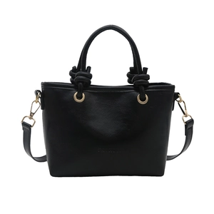 Minimalist black leather bucket tote bag with unique woven knot handles and shoulder strap