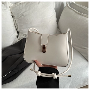 Detail of cream white shoulder bag with vintage wood grain buckle and knotted strap