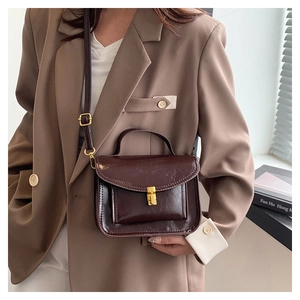 Detail of vintage dark brown faux leather crossbody bag with golden metal buckle clasp