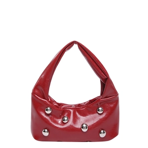 Sac à main rouge en cuir verni brillant avec clous argentés sur fond blanc neutre