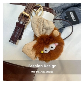 Détail d'un porte-clés monstre en peluche marron avec de grands yeux sur un sac à main