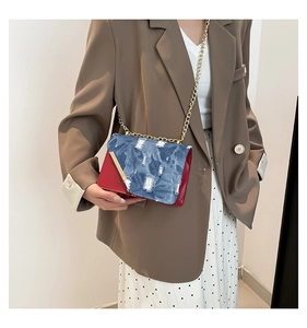 Dettaglio della borsa a tracolla in denim color block con catena dorata sulla modella