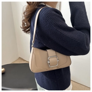 Detail of beige faux leather shoulder bag with a large silver square buckle buckle