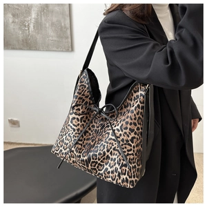 Detail of leopard print shoulder bag featuring a black leather bow and long strap