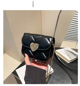 Détail d'un mini sac matelassé noir avec une boucle métallique dorée en forme de cœur