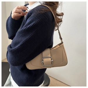 Close-up of a beige faux leather baguette bag featuring a large silver square buckle