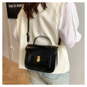 Détail d'un sac à main noir classique avec fermoir doré et poignée supérieure