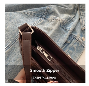 Detail shot of smooth silver zipper and monogram pattern on brown underarm bag