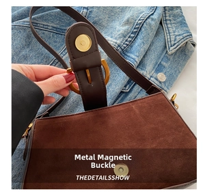 Detail der braunen Wildleder-Schultertasche mit goldener Magnetschnalle auf Denim