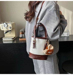 Détail du sac seau rétro bicolore avec pendentif en peluche et longue bandoulière