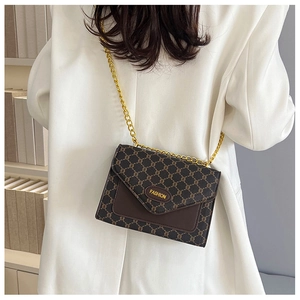 Gros plan du sac bandoulière vintage avec chaîne dorée sur un blazer blanc