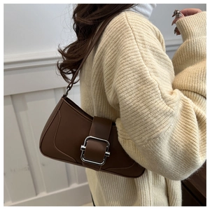 Detail of a brown leather shoulder bag featuring a prominent silver buckle on the front