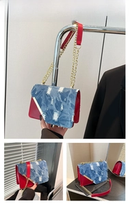 Dettaglio della borsa a tracolla in denim invecchiato e pelle rossa con catena oro
