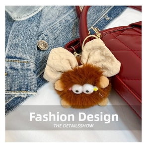 Detail of brown plush elf keychain with big eyes on a red quilted leather bucket bag