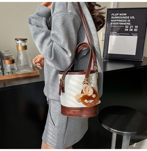 Détail du sac seau bicolore blanc et marron avec un joli pendentif monstre
