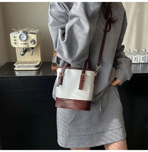 Détail du sac seau bicolore avec texte FASHION & BAGS et bandoulière réglable en cuir
