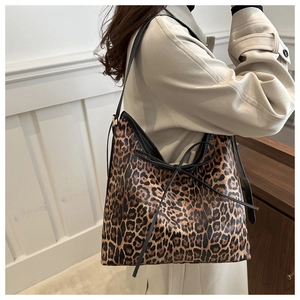 Close-up of leopard print tote bag featuring a black bow tie and slim shoulder strap