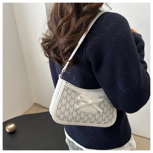 Detail showing beige monogram shoulder bag with leather bow decoration on a model