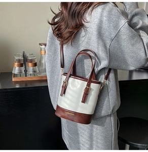 Détail d'un sac seau chic montrant le cuir beige et marron avec boucle métallique