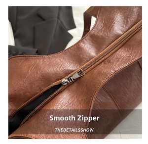 Detail of smooth silver zipper on a premium brown leather motorcycle shoulder bag