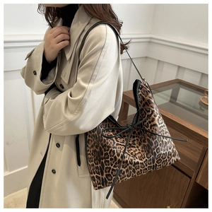 Close-up of leopard print tote bag with black bow detail worn by a model in beige coat