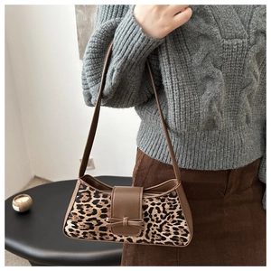 Detail der Leopard-Baguette-Tasche mit Lederriemen und Schleife auf einem Strickpullover