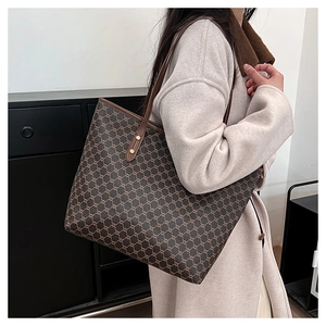 Detail of vintage monogram tote bag featuring leather handles and golden metal rivets