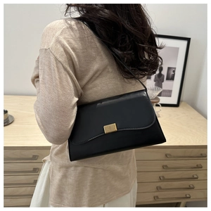 Detail of black faux leather shoulder bag featuring a wave edge flap and gold metal lock