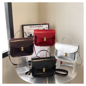 Détail de quatre sacs bandoulière rétro en marron, rouge, argent et noir avec boucles métal