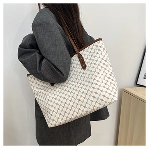 Detail of large tote bag with retro monogram print and premium brown leather straps